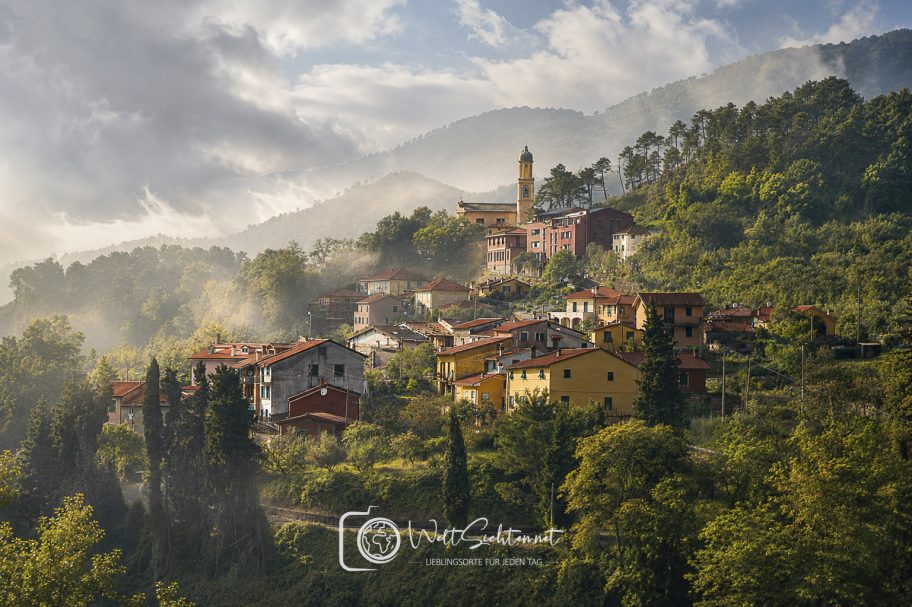 Ligurisches Bergdorf zwischen grünen Hängen und mediterraner Landschaft in Italien