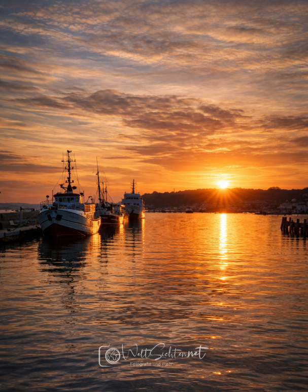 Sonnenuntergang im Hafen von Sassnitz auf Rügen Sonnenuntergang über einem Hafen mit Booten und spiegelndem Wasser.